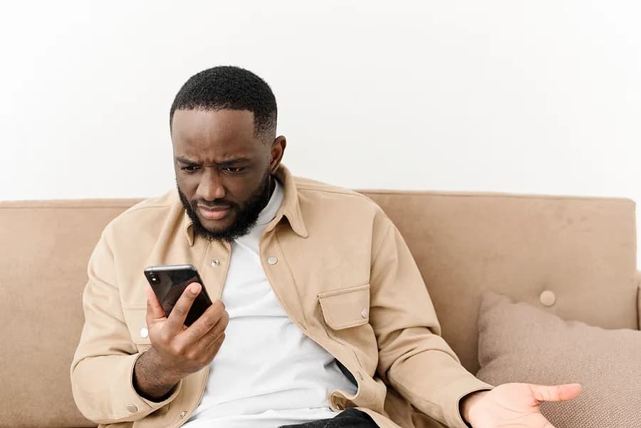 homem no sofá com o celular na mão