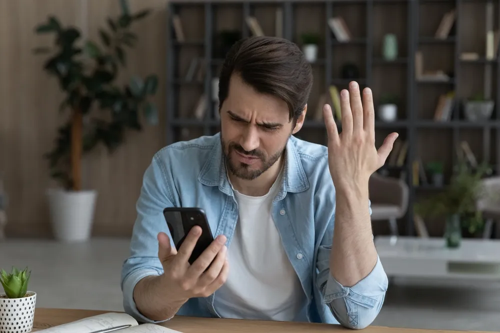 homem confuso com o celular
