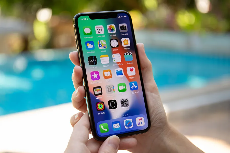Mão segurando um iPhone ao ar livre para mostrar o que é o True Tone no iPhone.