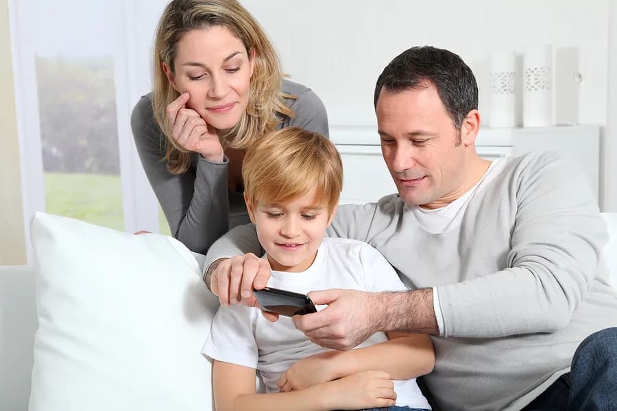 Mãe, pai e filho olhando para um celular.