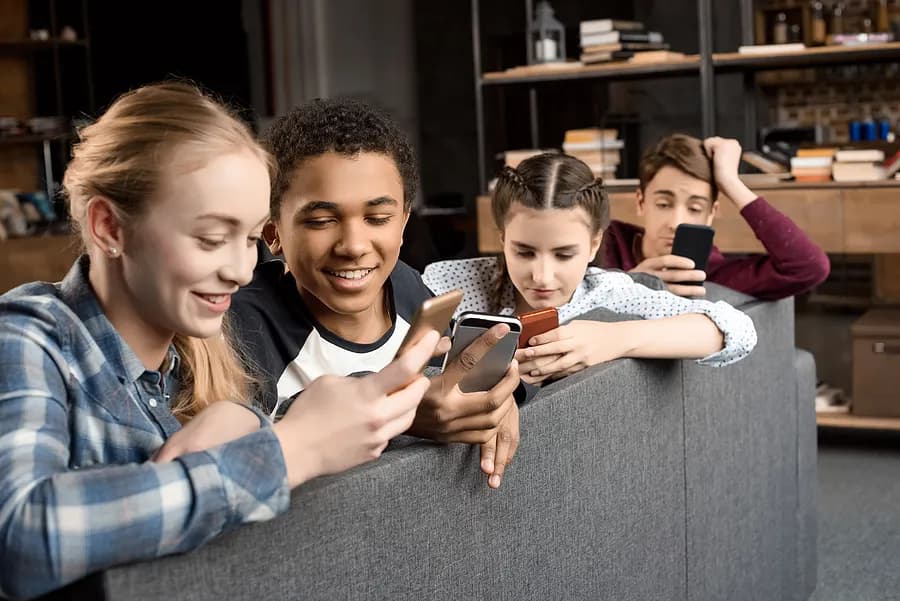 Quatro adolescentes olhando para seus celulares.