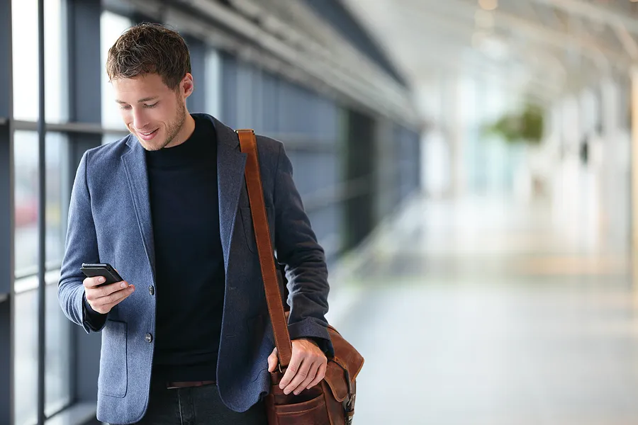Homem caminhando com o celular na mão.