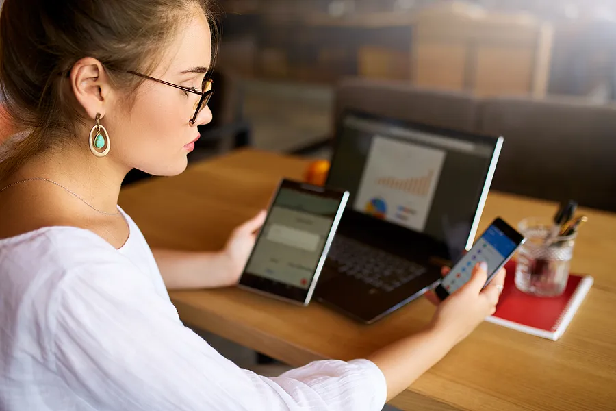 Mulher com celular, tablet e laptop.