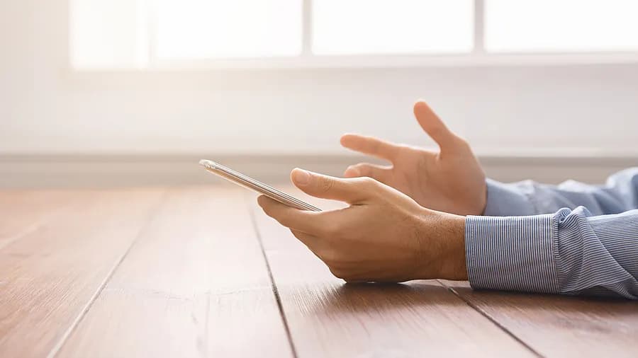 Pessoa segurando um iPhone perto de uma janela, ilustrando como desbloquear o código de acesso do iPhone sem usar um computador.