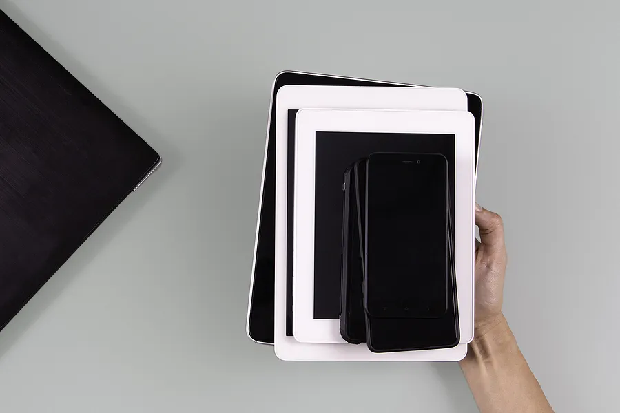Mão segurando dispositivos móveis empilhados, incluindo smartphones e tablets, simbolizando o mercado em crescimento e as tendências futuras dos aparelhos recondicionados